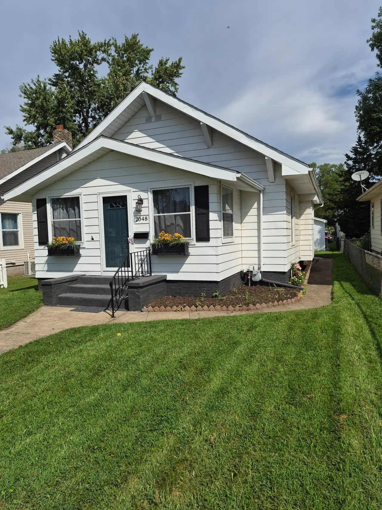 White Des Moines bungalow with a freshly mowed and edged striped front lawn