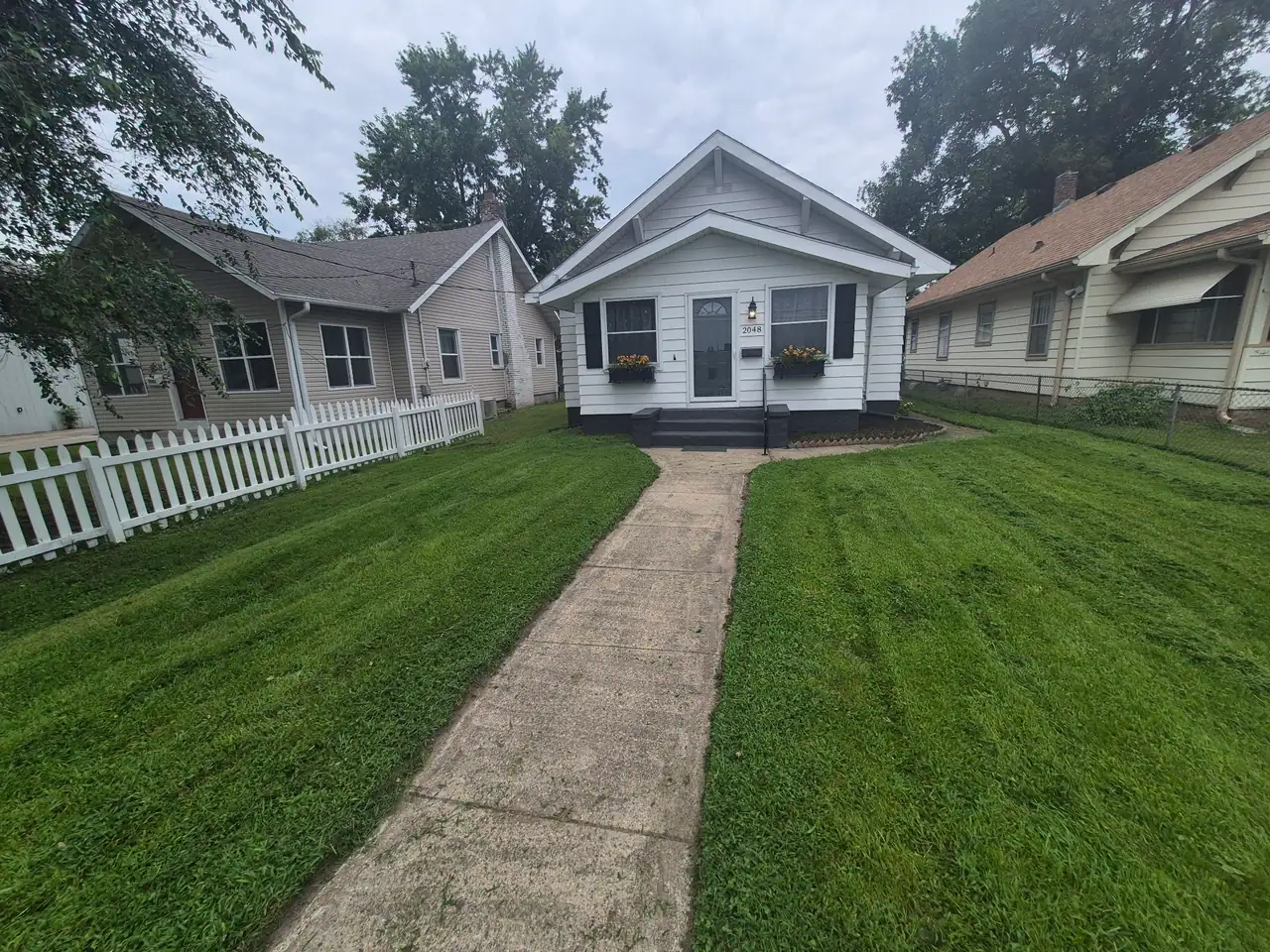 Freshly mowed and striped front lawn at a white Des Moines bungalow